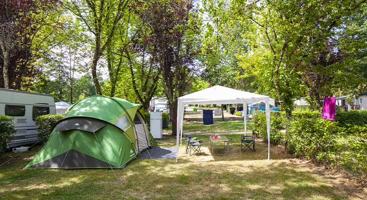 tente et barnum installés sur un emplacement ombragé du camping